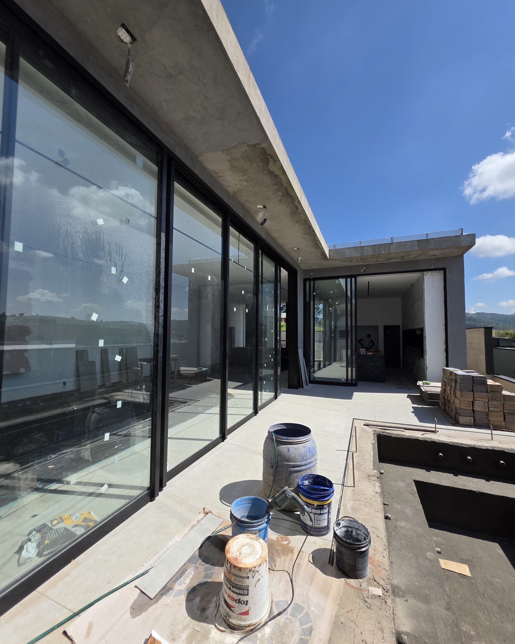 Residência contemporânea com fachada de vidro, concreto aparente e área de piscina